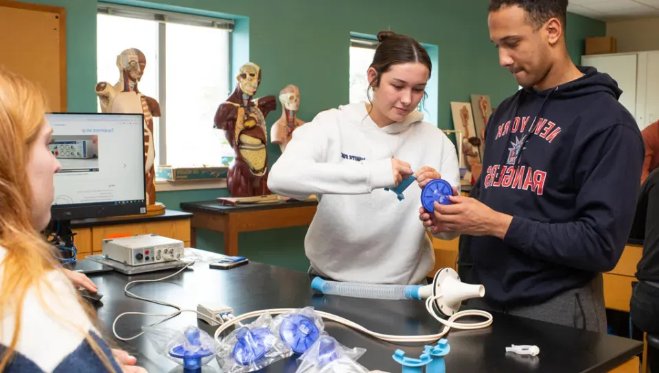 Two students prepare a medical tool for testing lung capacity